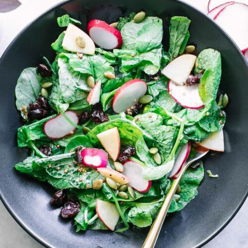 radish greens salad in a black bowl on a white table