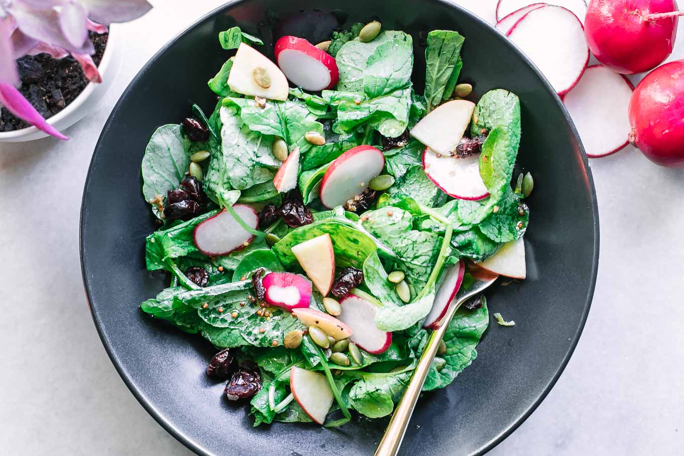 radish greens salad in a black bowl on a white table