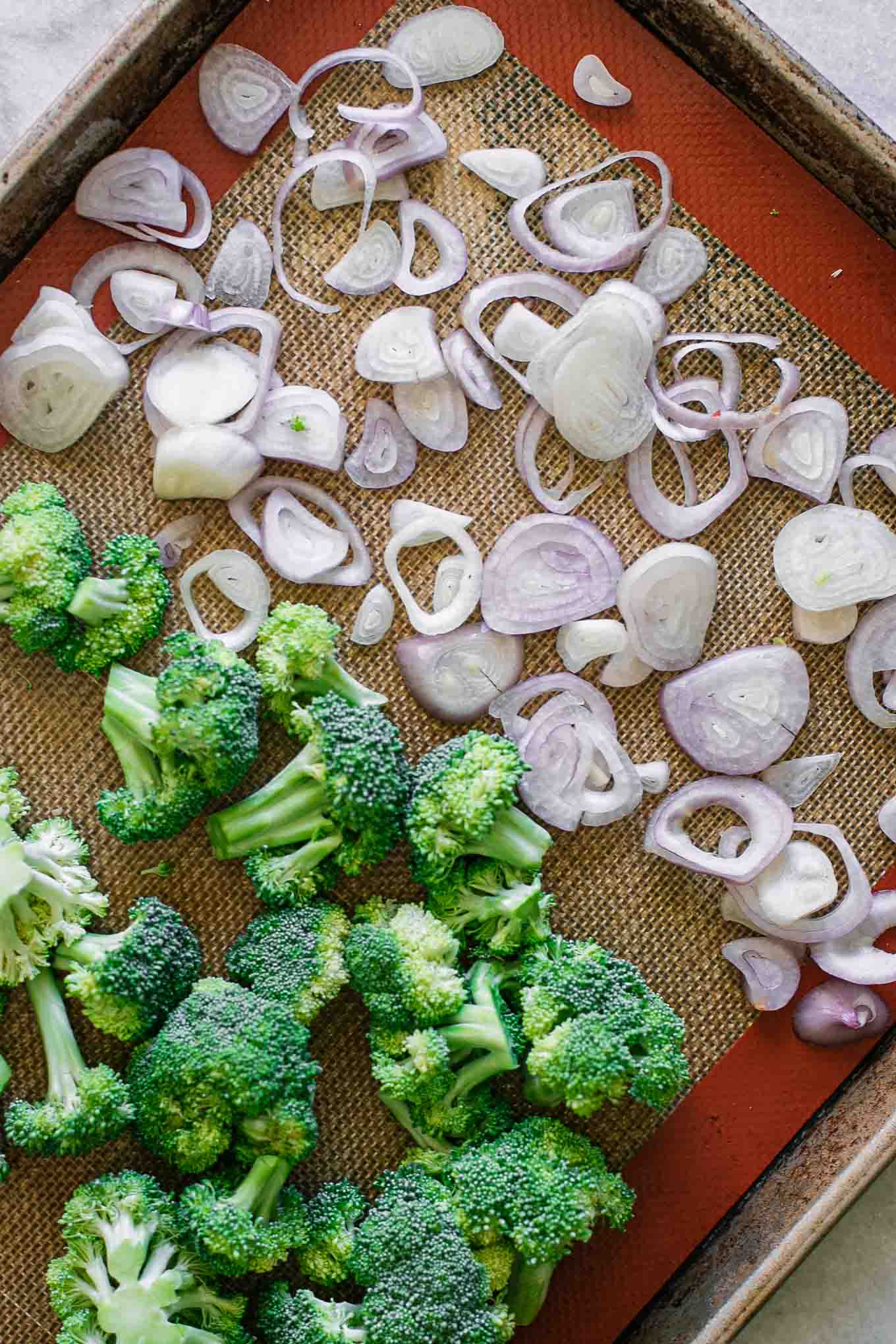 cut broccoli florets and sliced shallots on a baking sheet before roasting