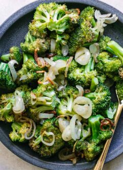 baked broccoli and shallots on a blue plate with a gold fork
