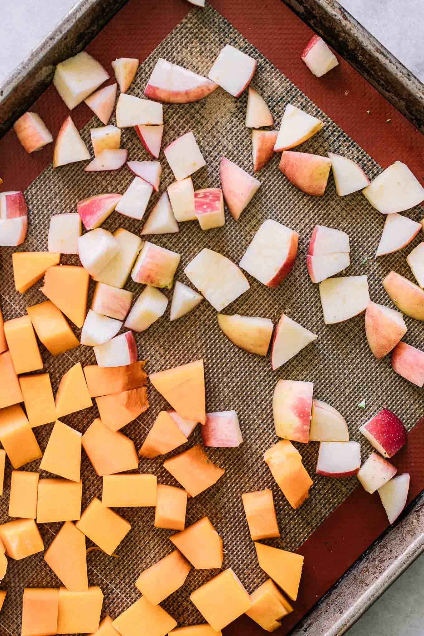 cut butternut squash and apples on a baking sheet before roasting