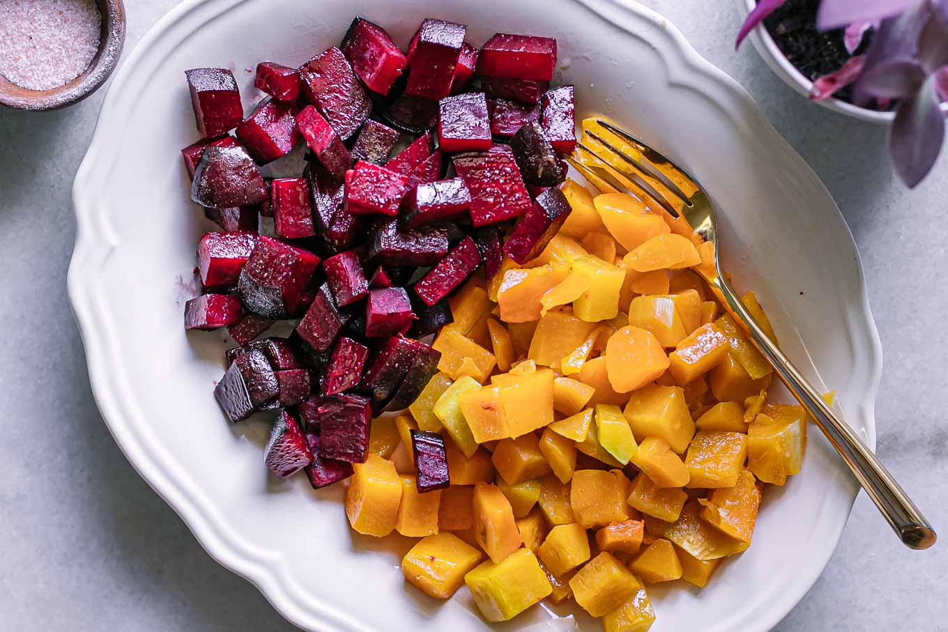 baked butternut squash and beets on a white serving dish with a gold fork