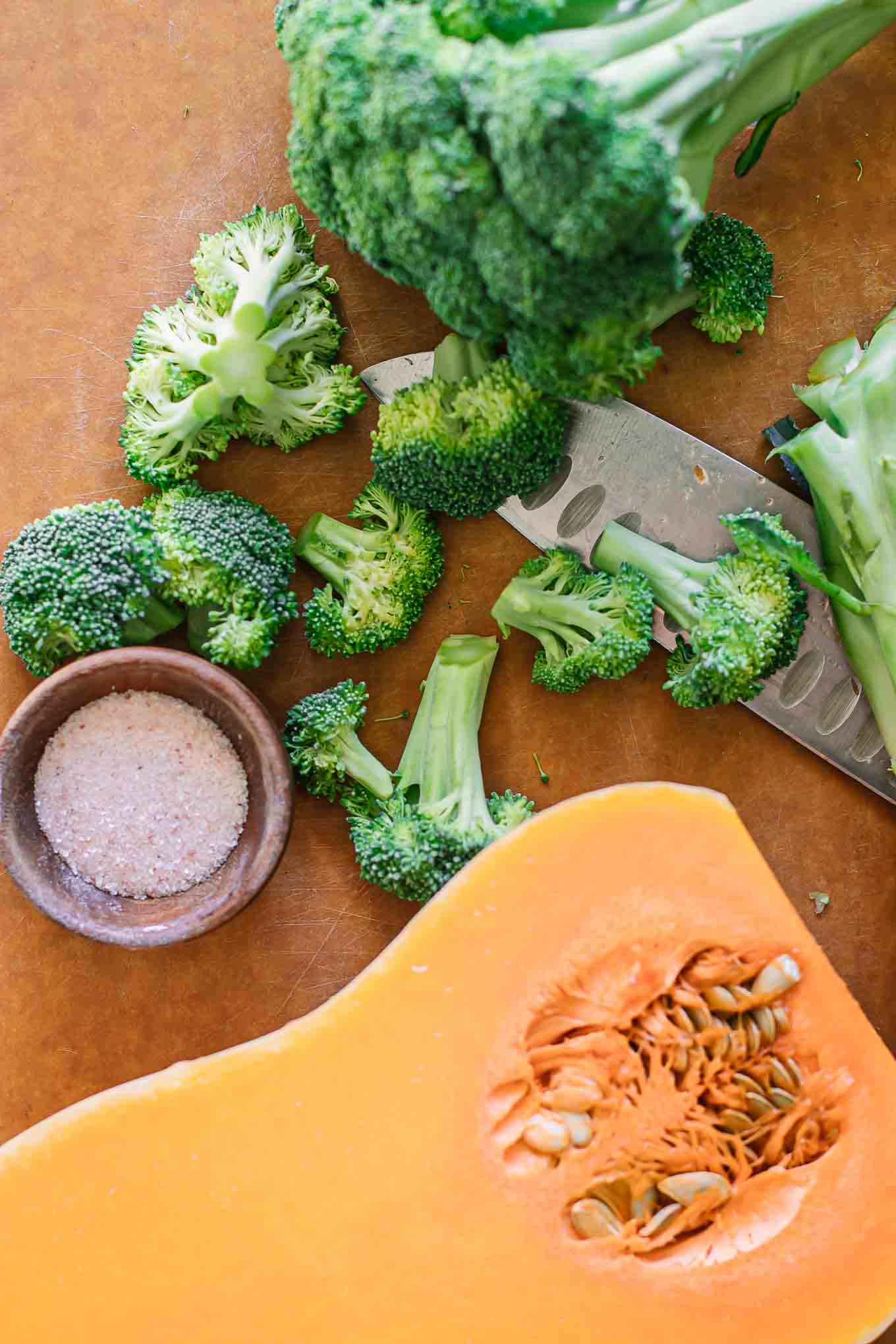 cut butternut squash and broccoli florets on a cutting board with a knife