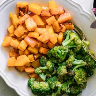 baked broccoli and butternut squash on a white plate with a gold fork