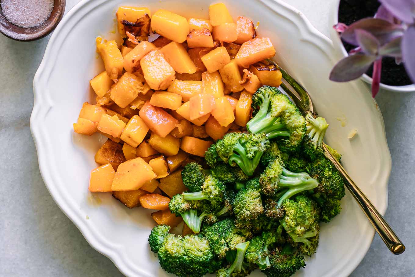 baked broccoli and butternut squash on a white plate with a gold fork