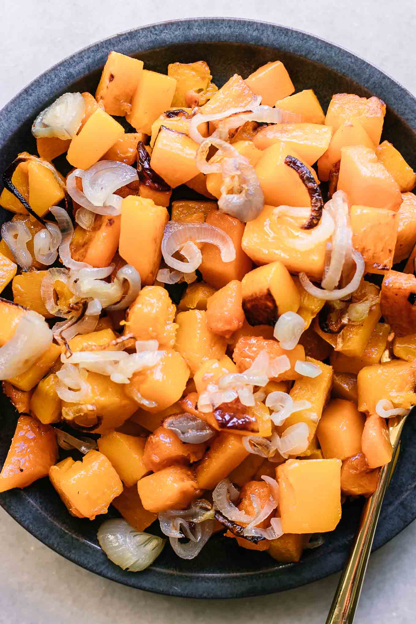 a butternut squash and shallots side dish with a gold fork