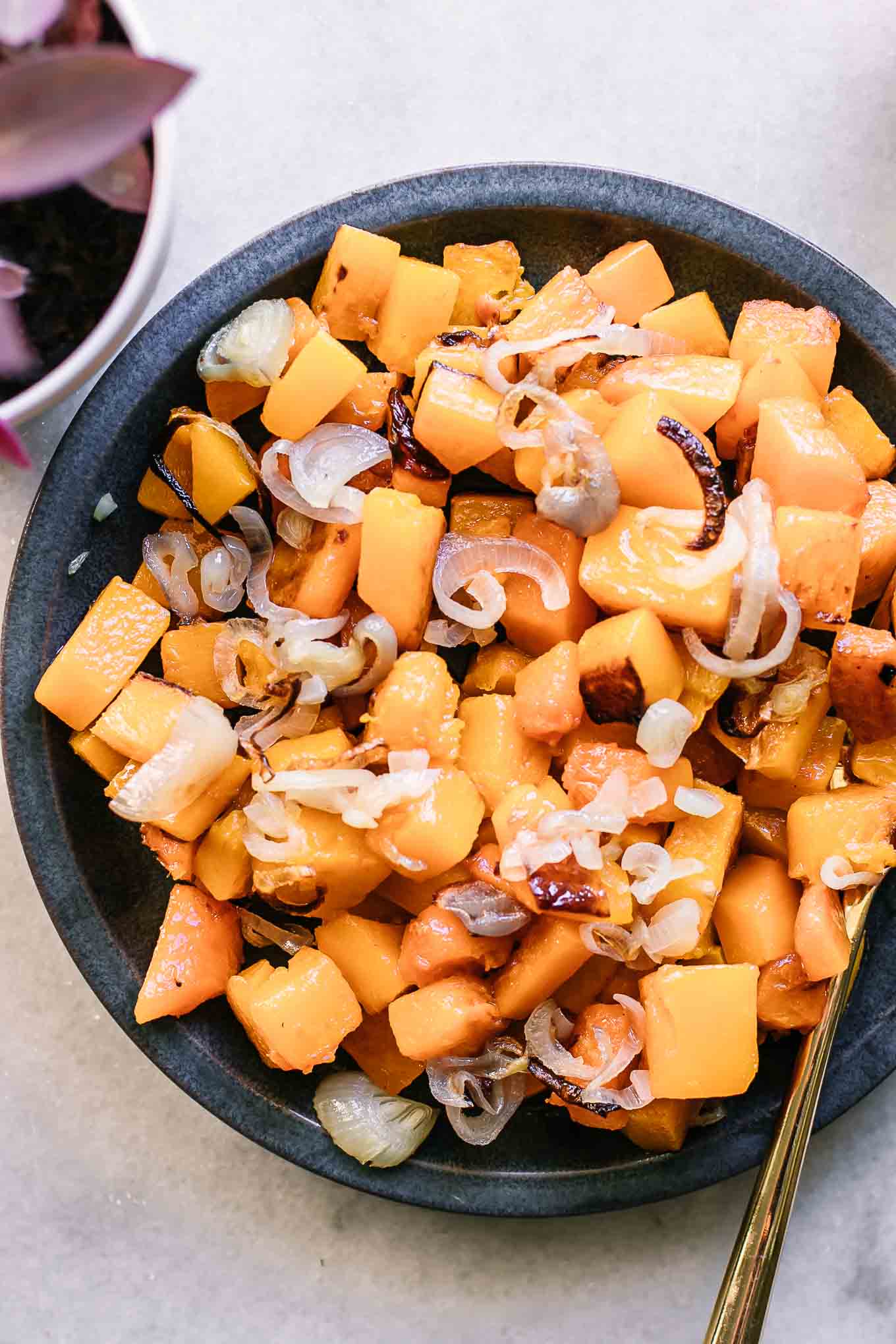 roasted butternut squash and shallots on a blue side dish