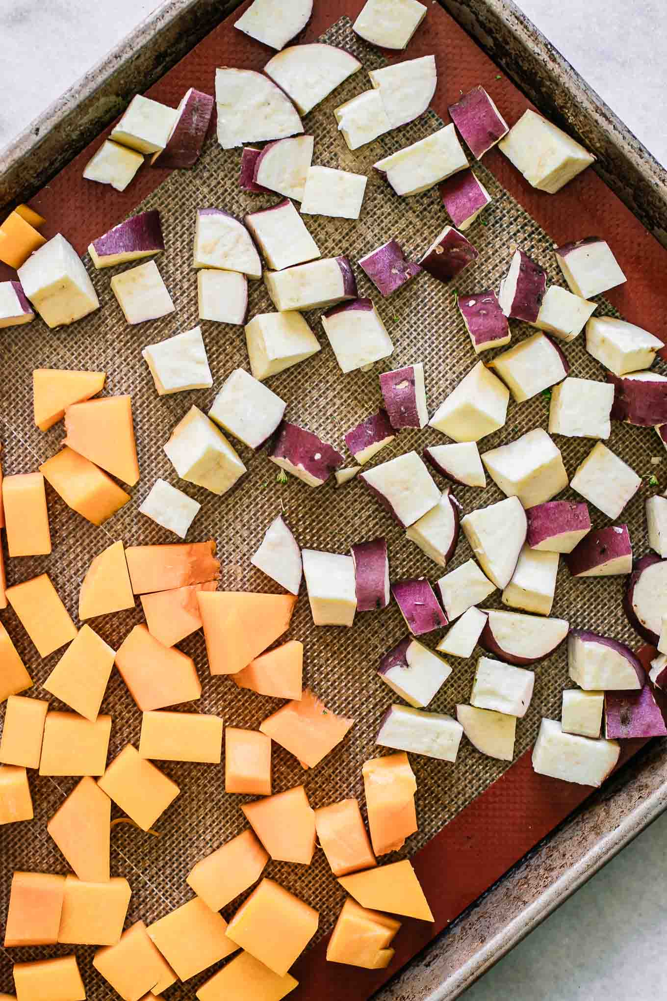 Sweet potatoes and butternut squash on a baking sheet before roasting