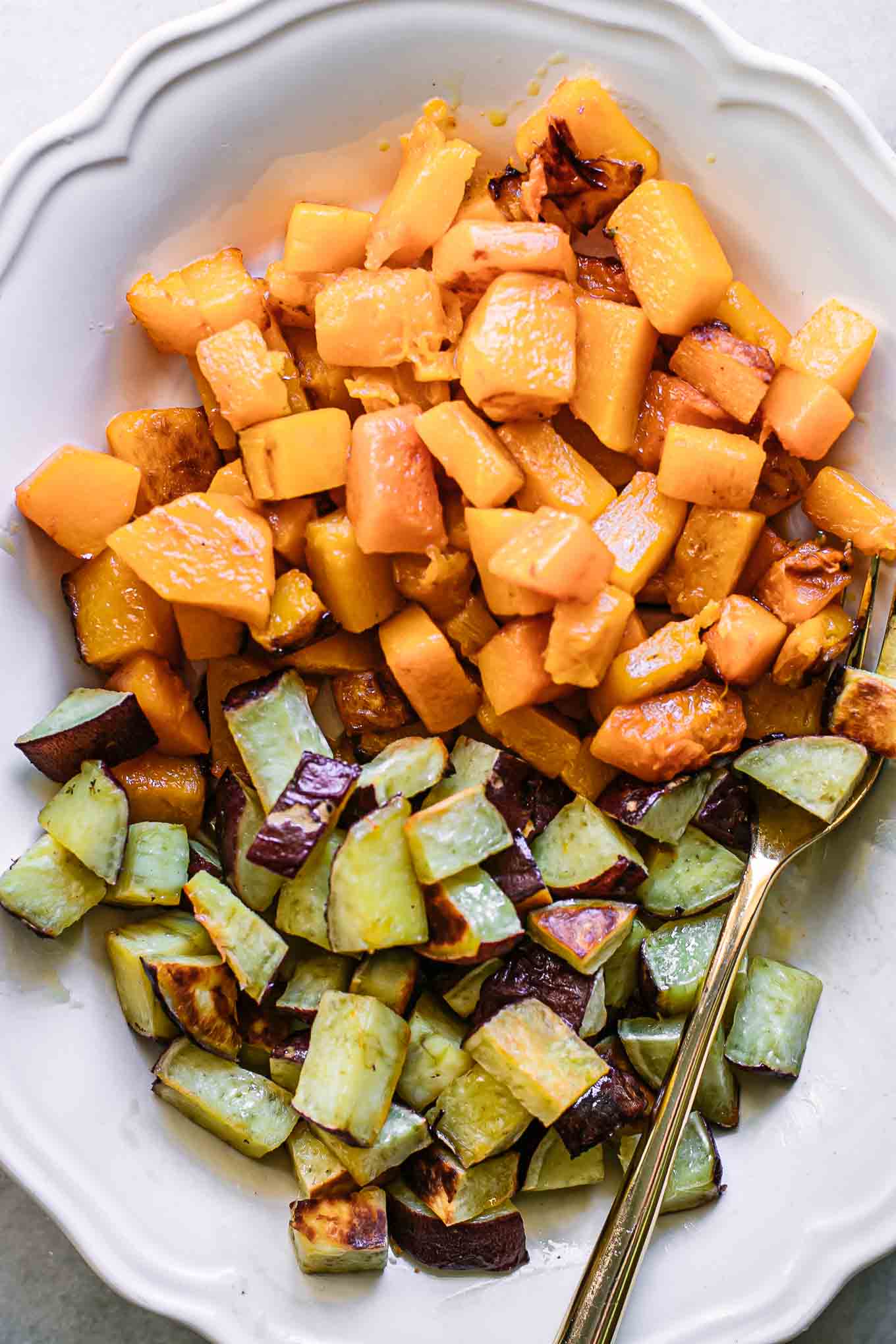close up photo of roasted sweet potatoes and butternut squash on a white plate