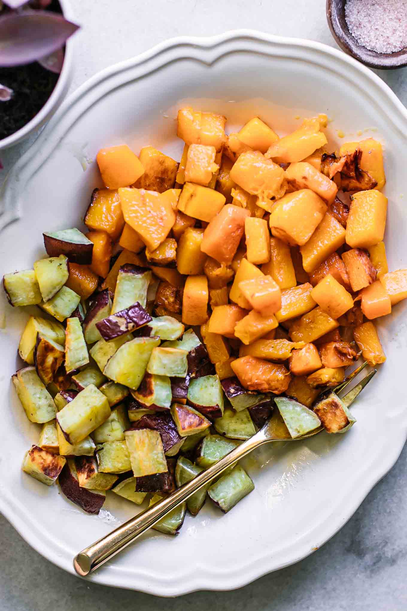 roasted butternut squash and sweet potatoes on a white plate with a gold fork