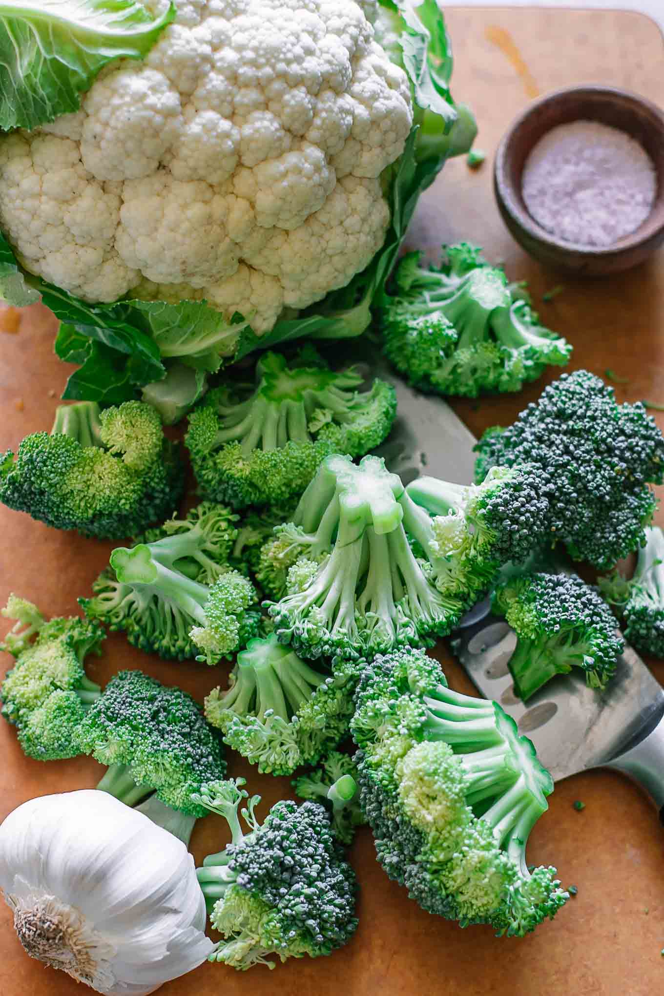 cut broccoli florets on a cutting board with cauliflower