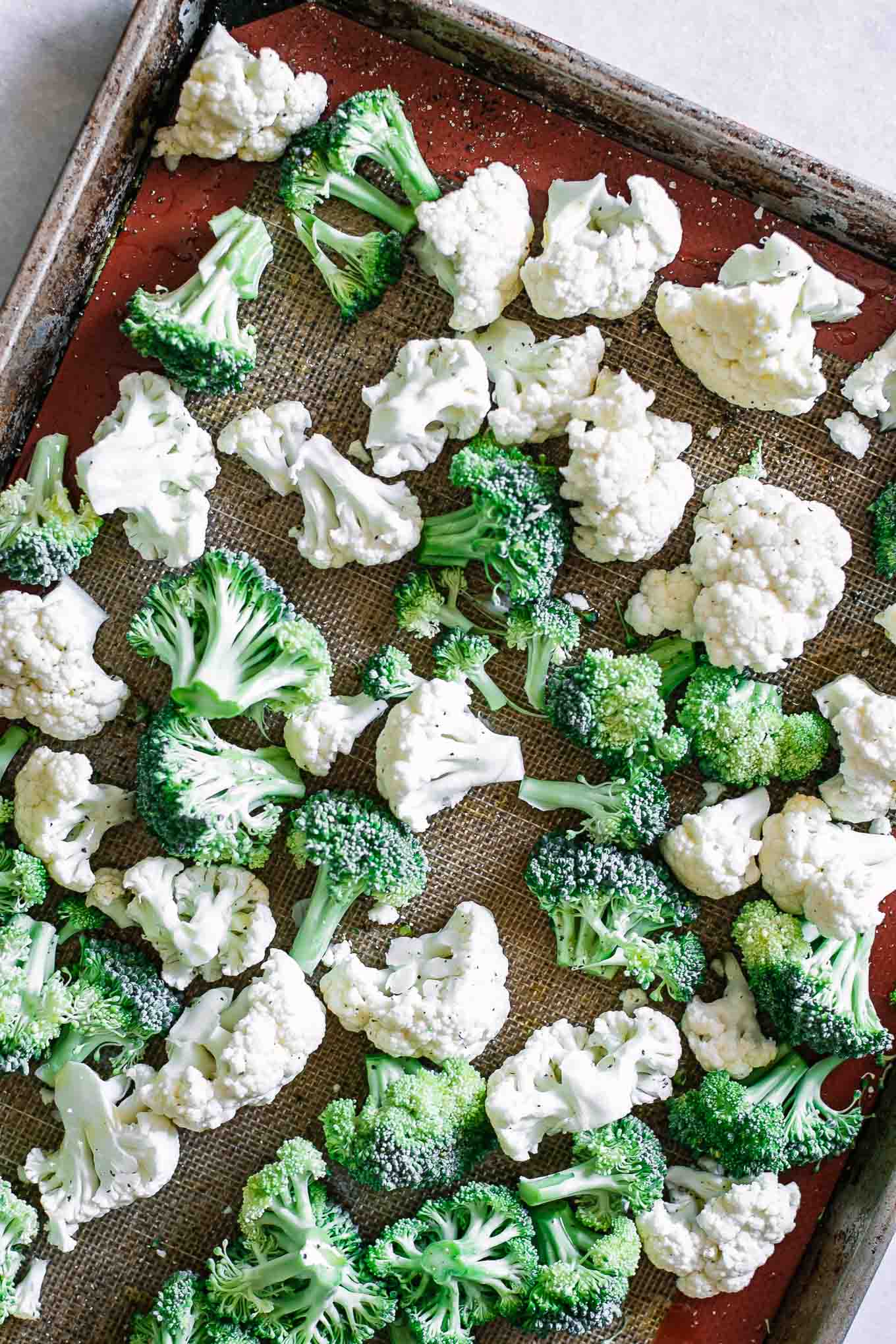 cauliflower and broccoli on a baking sheet before roasting