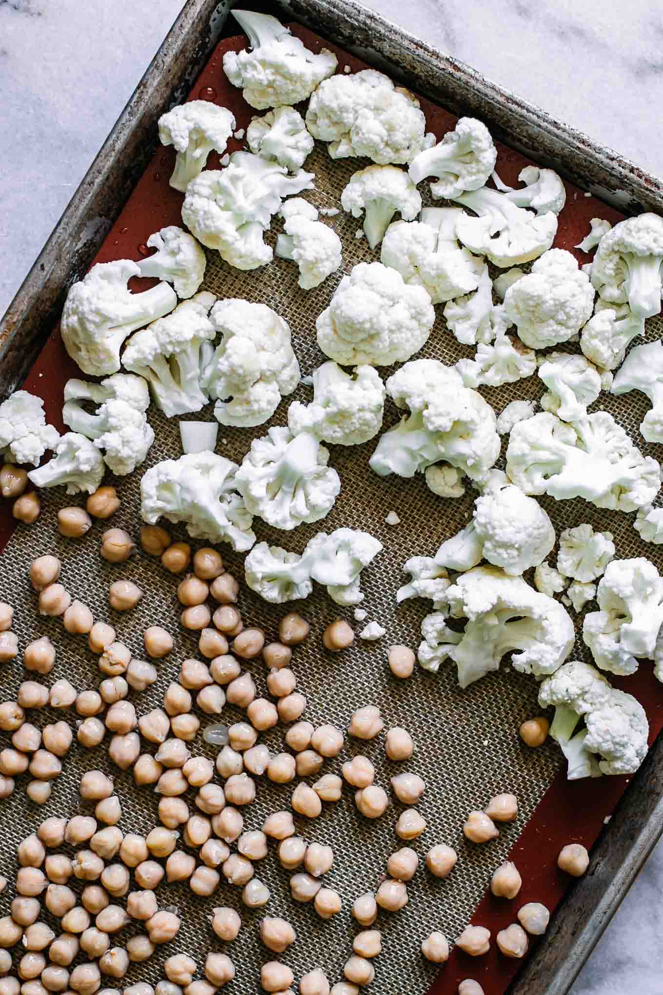 a baking sheet with cauliflower florets and chickpeas before roasting