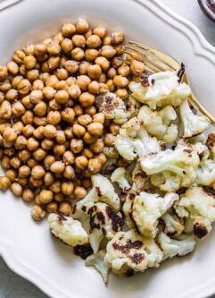 a white side dish with baked chickpeas and cauliflower on a white table