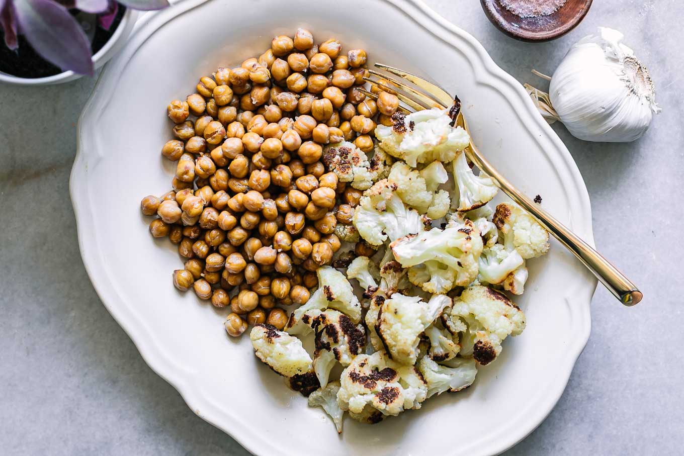 a white side dish with baked chickpeas and cauliflower on a white table