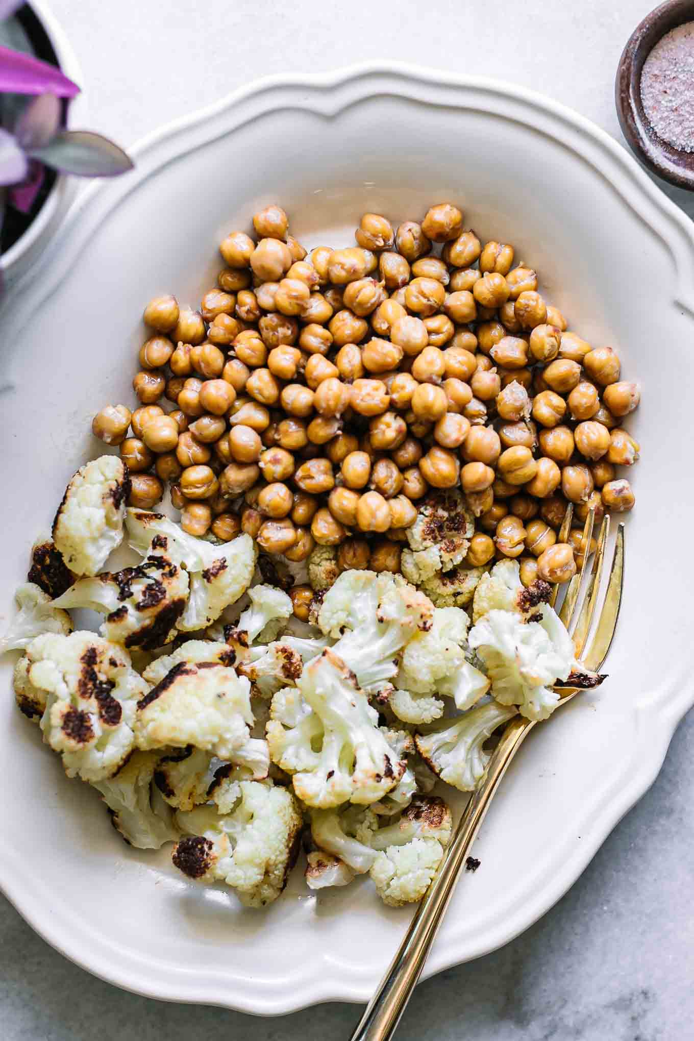 roasted cauliflower and chickpeas on a white plate with a gold fork