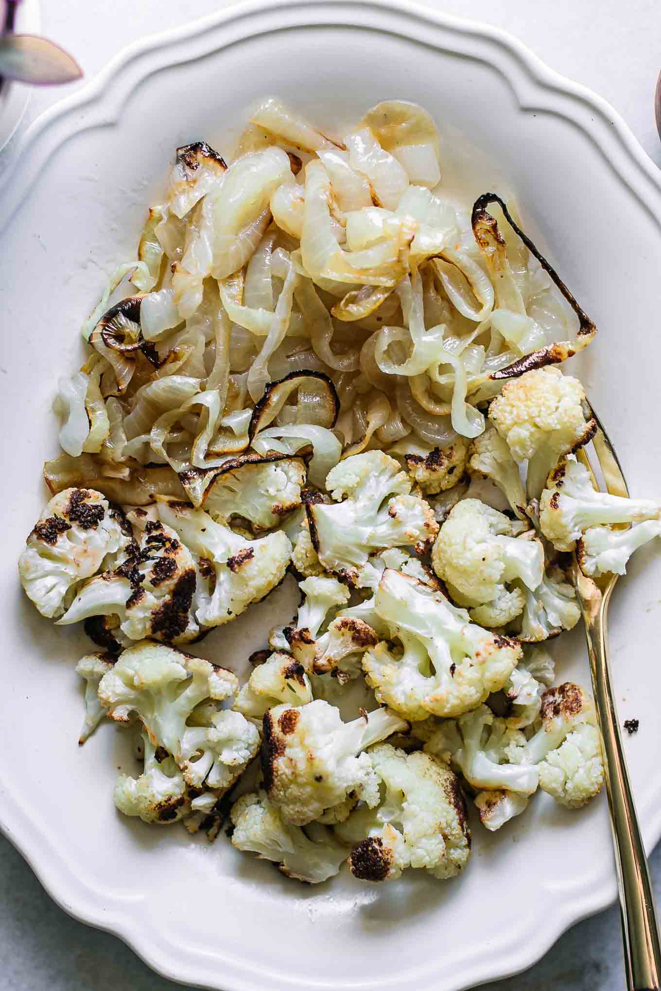 a close up photo of baked cauliflower and onions on a white plate