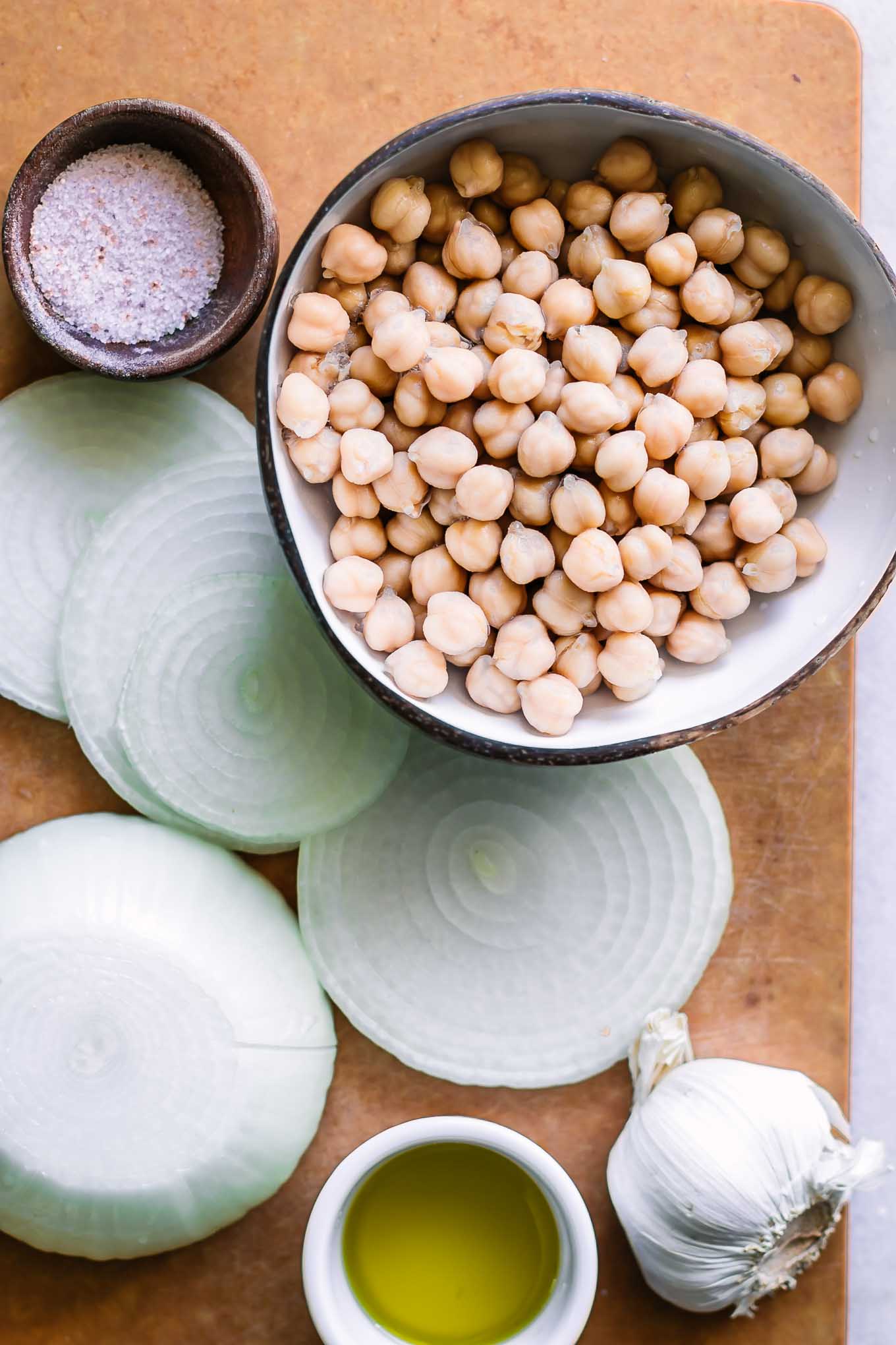 cut onions and drained chickpeas on a wood cutting board