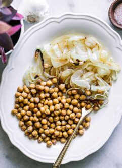 roasted chickpeas and onions on a white plate with a gold fork