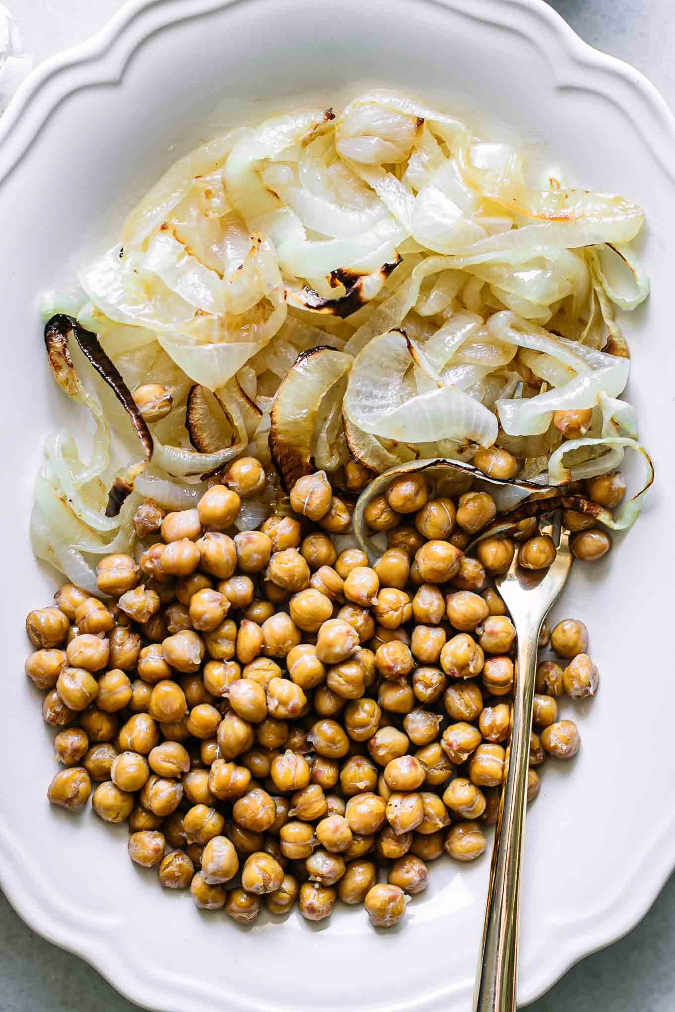 a close up photo of roasted onions and chickpeas side dish on a white plate