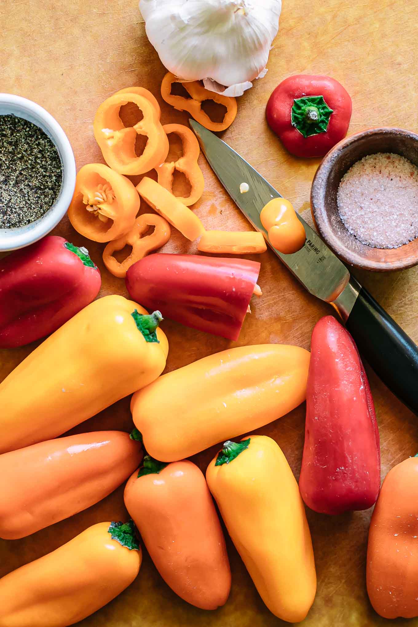 cut and whole mini peppers on a cutting board with a knife