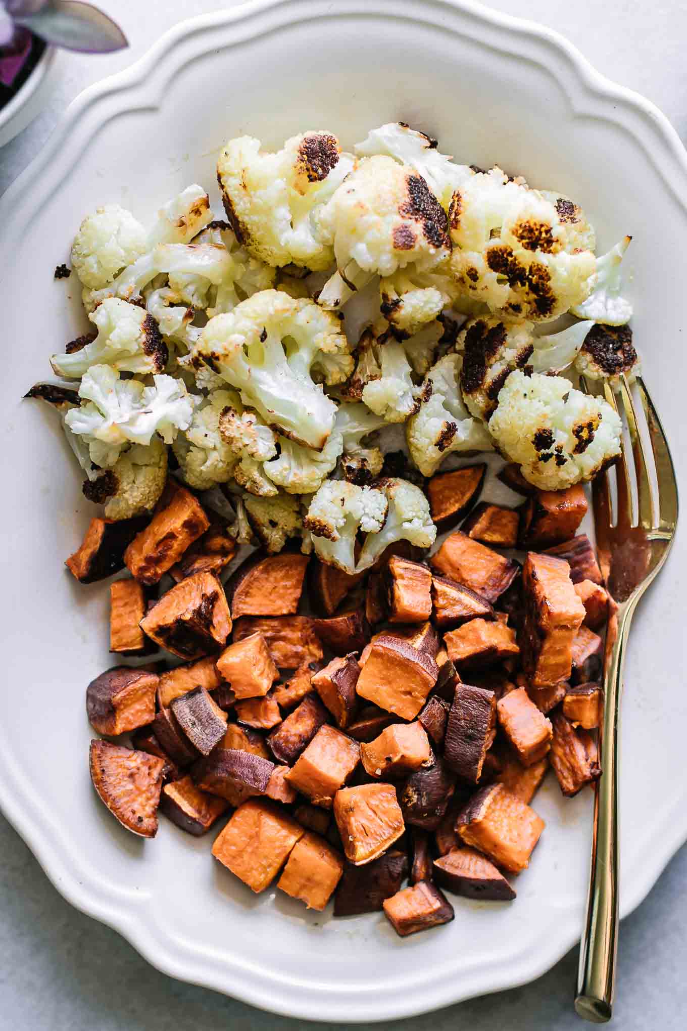 a white plate with roasted sweet potatoes and cauliflower