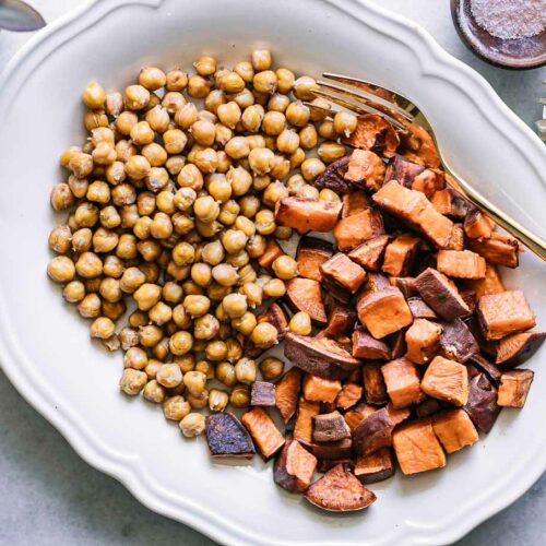 baked sweet potatoes and chickpeas on a white plate with a gold fork