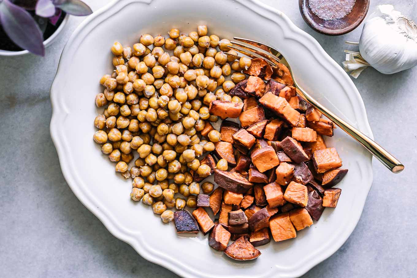 baked sweet potatoes and chickpeas on a white plate with a gold fork