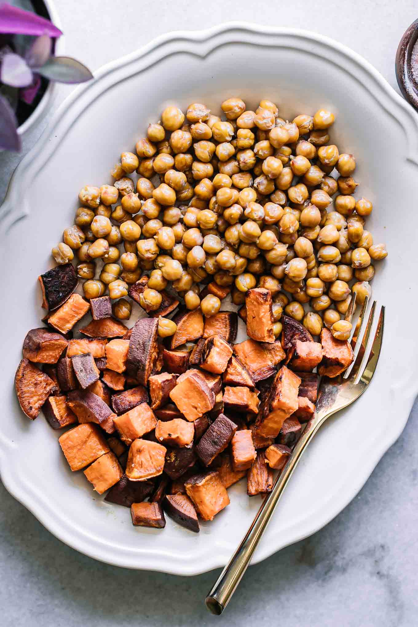 roasted chickpeas and sweet potatoes on a white plate with a gold fork