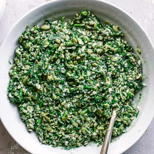 pesto with fresh dill inside white side dish bowl with a gold fork