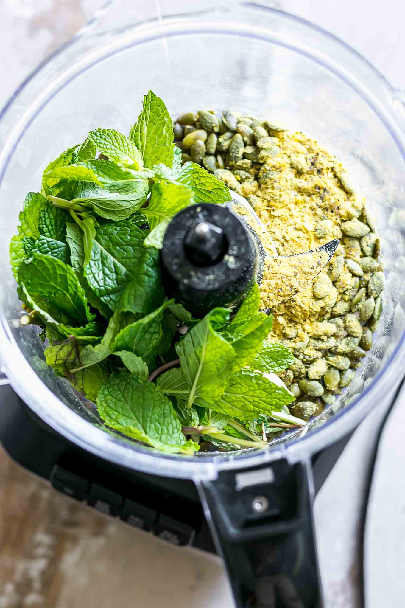 mint leaves with pesto ingredients in a food processor before blending