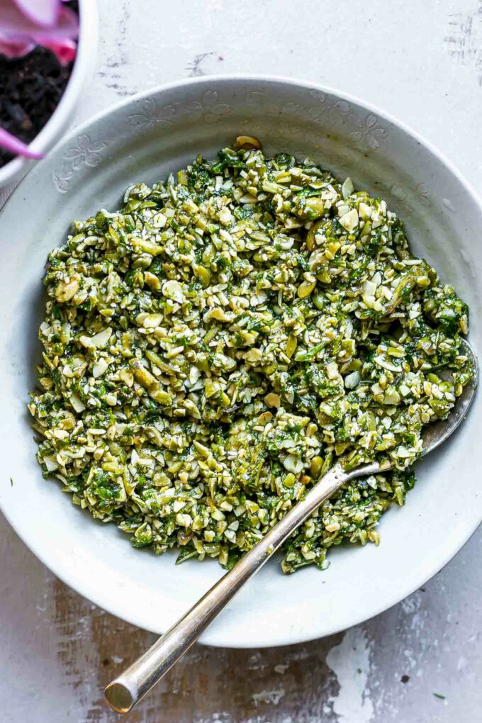 mint pesto sauce in a white bowl with a gold fork