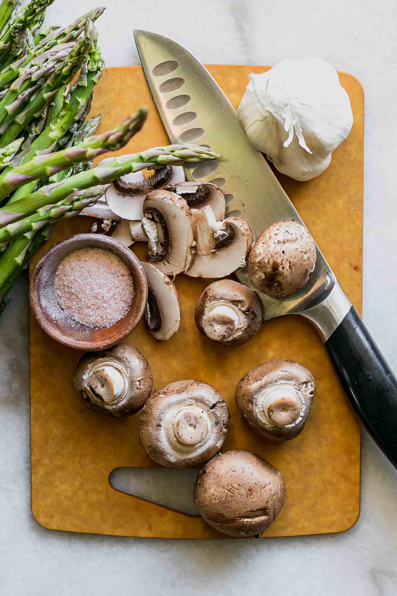 sliced mushrooms and asparagus on a wood cutting board