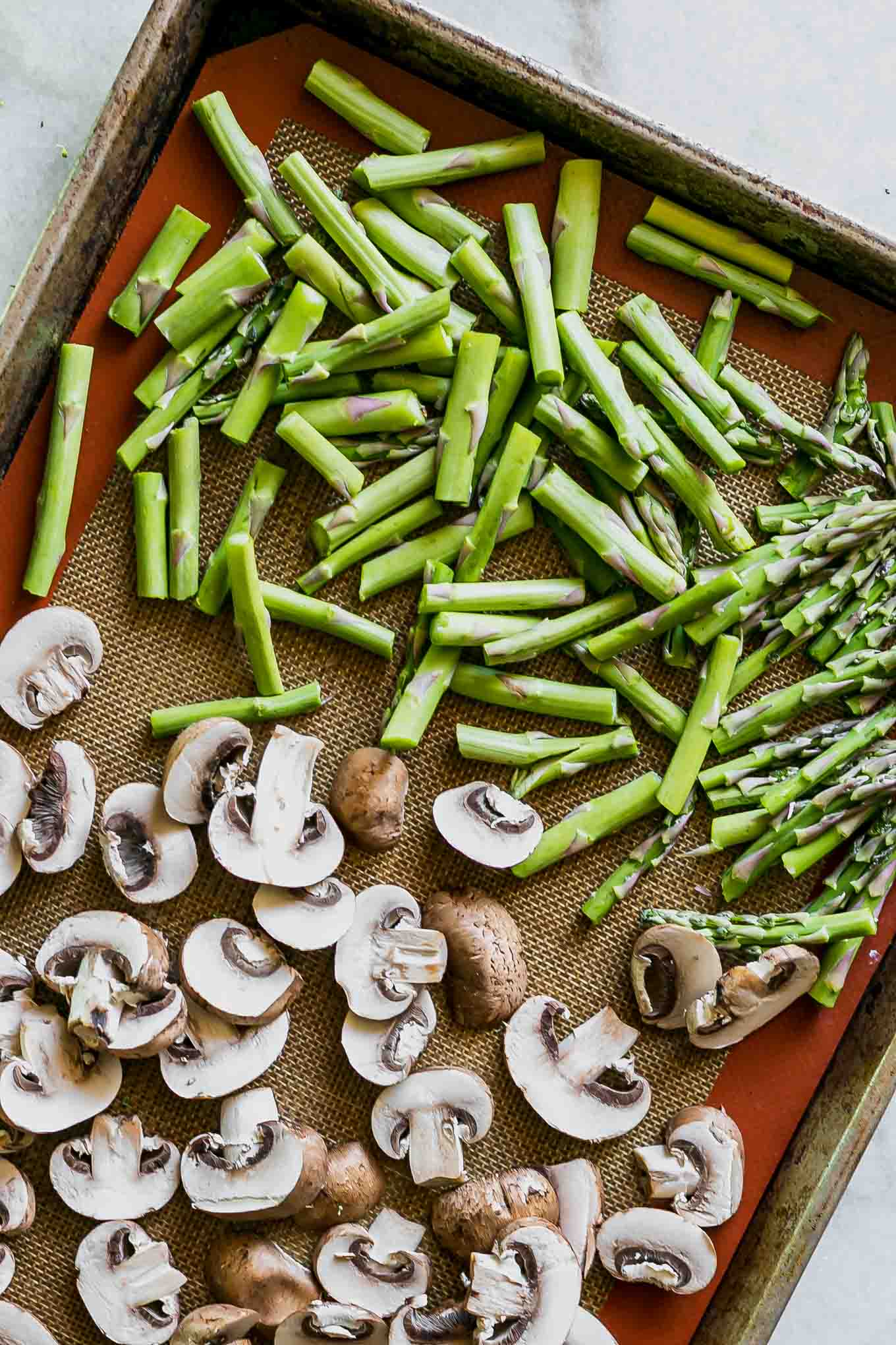 cut asparagus and mushrooms on a baking sheet before roasting