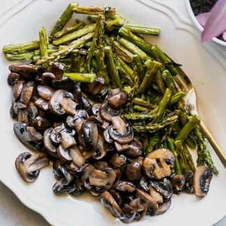 cut mushrooms and asparagus on a white plate with a gold fork