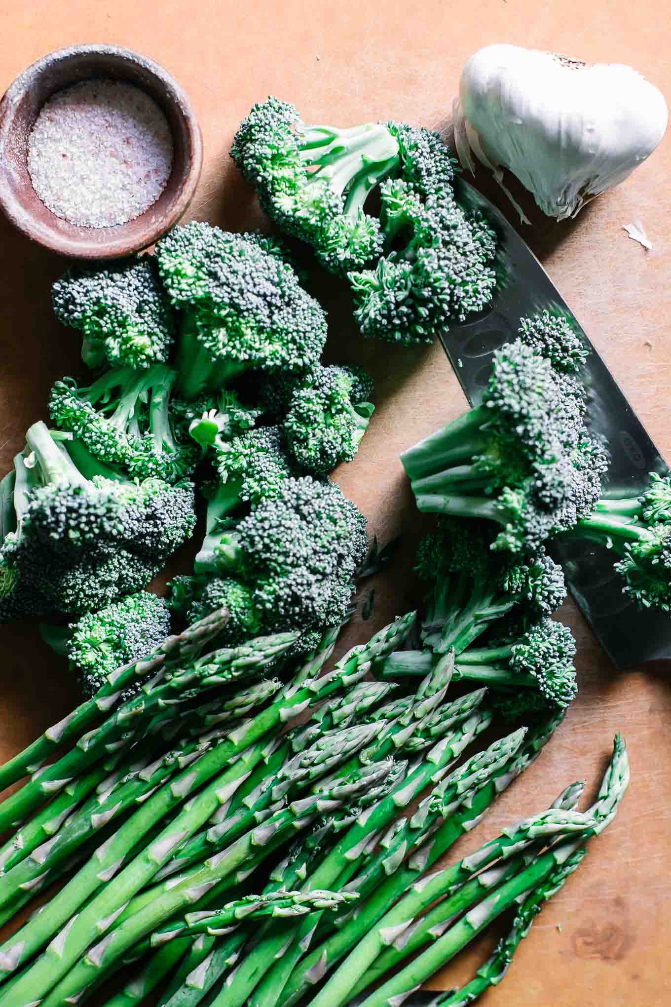 cut broccoli and asparagus on a wood cutting board