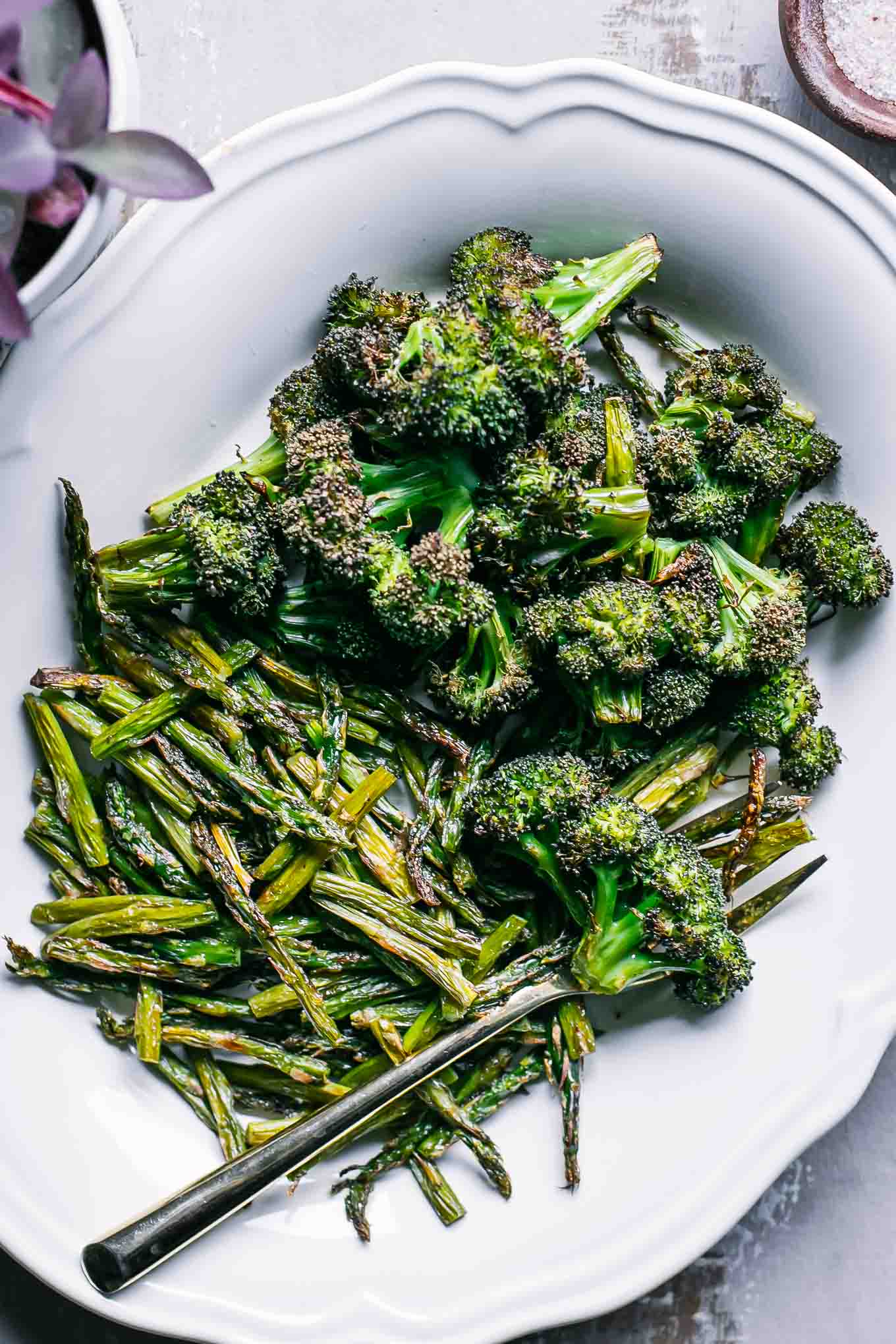 baked broccoli and asparagus on a white plate with a gold fork