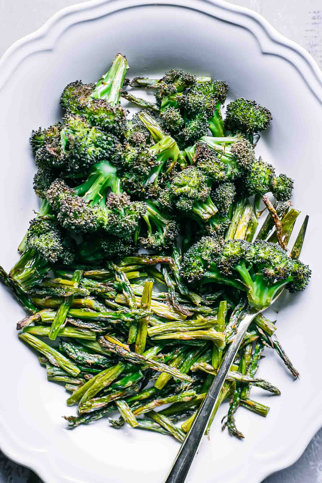 roasted broccoli and baked asparagus on a white plate