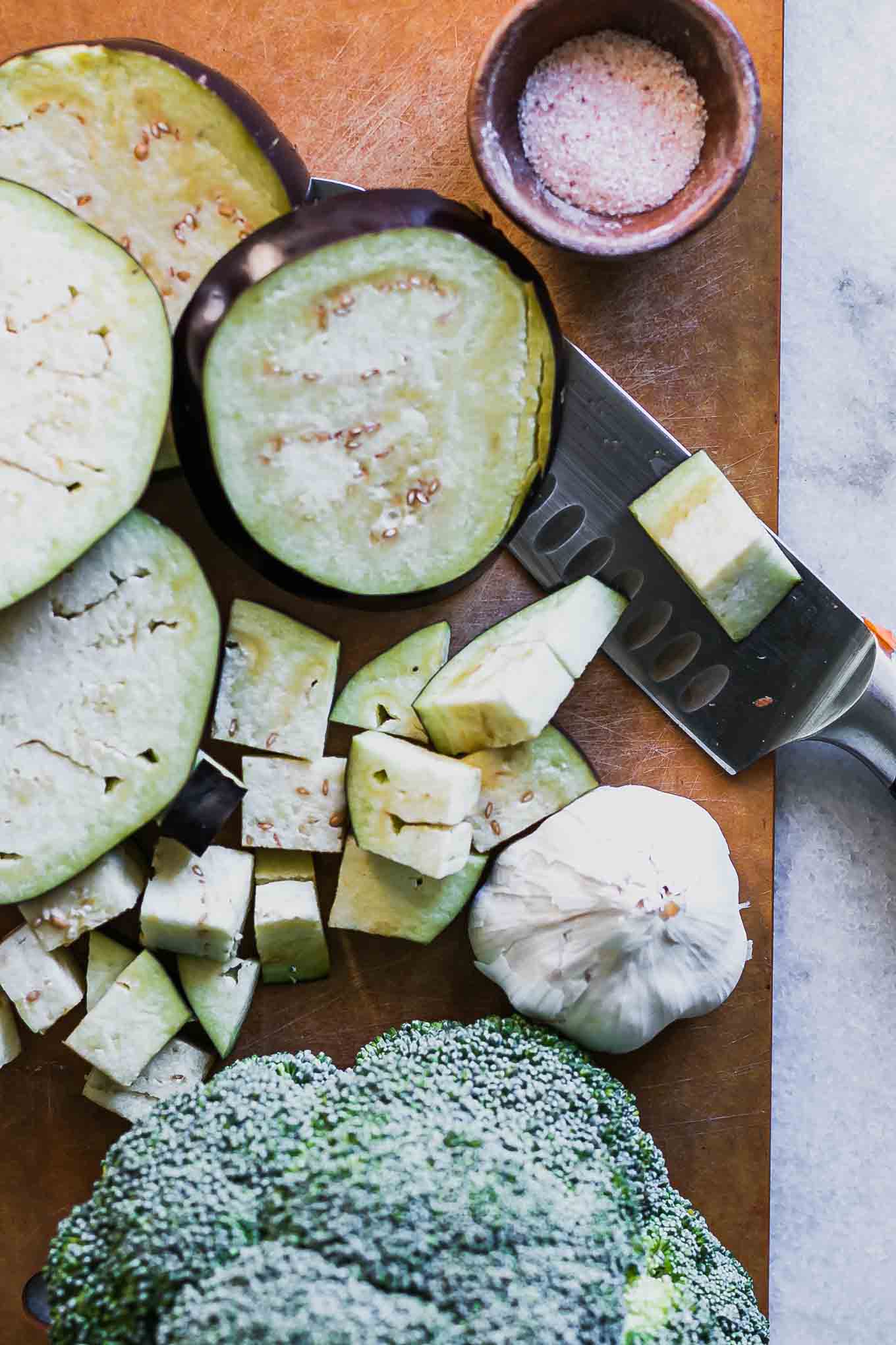 sliced eggplant and broccoli on a wood cutting board