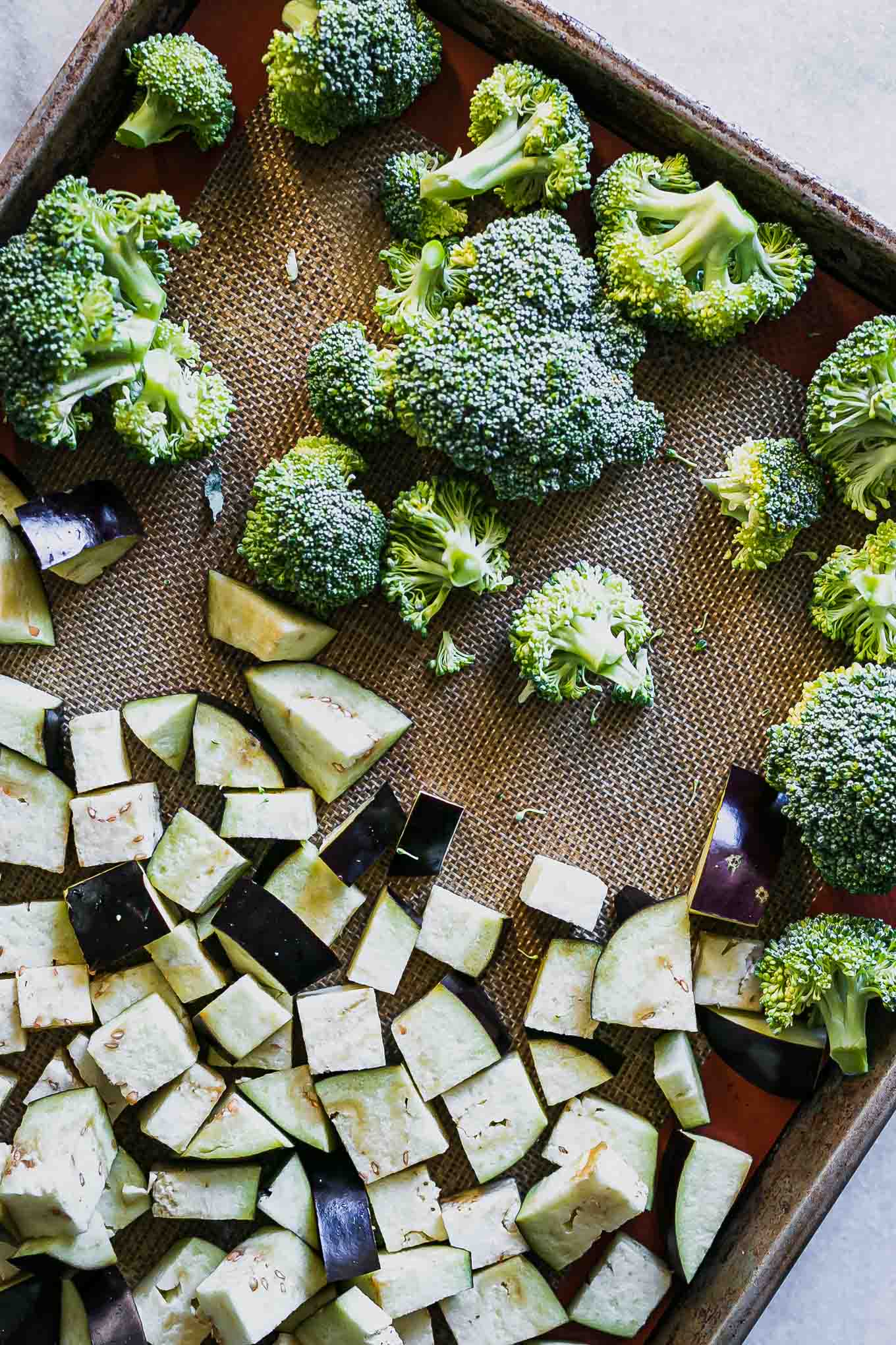 cut eggplant and broccoli on a baking sheet before roasting