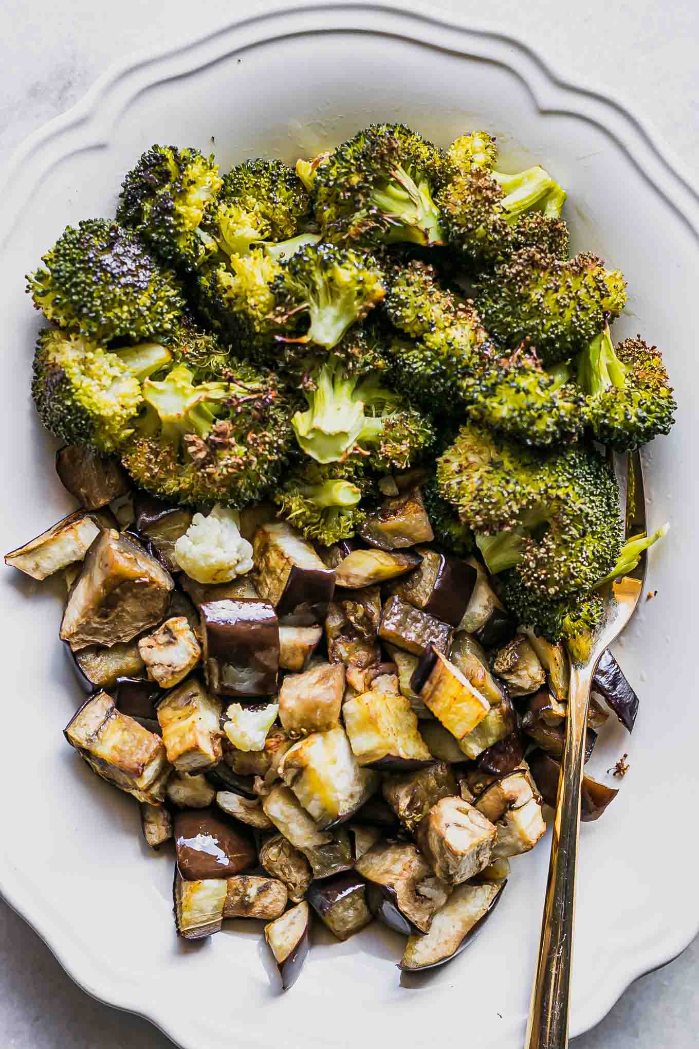 a close up photo of roasted eggplant and broccoli on a white plate