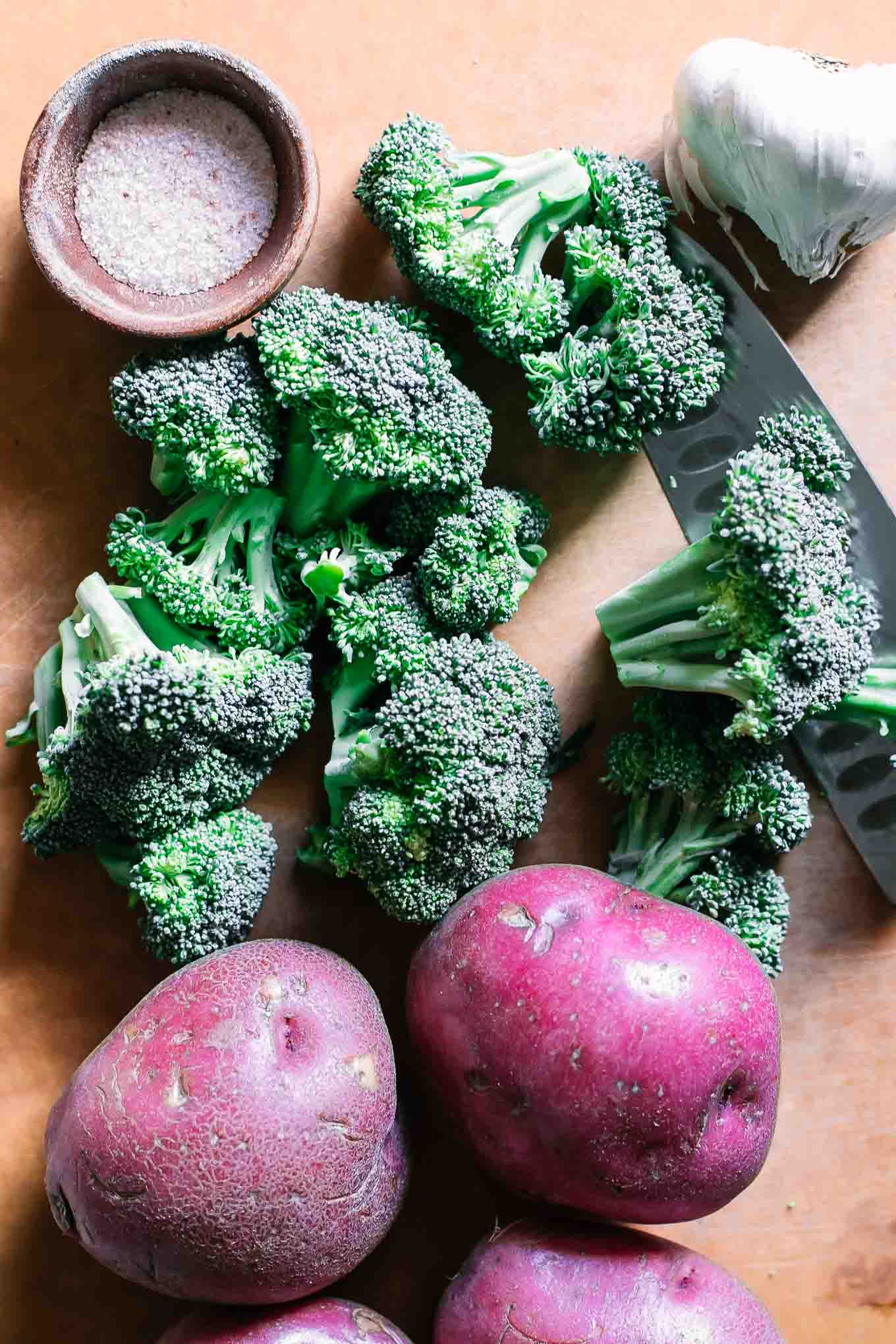 sliced broccoli and potatoes on a wood cutting board