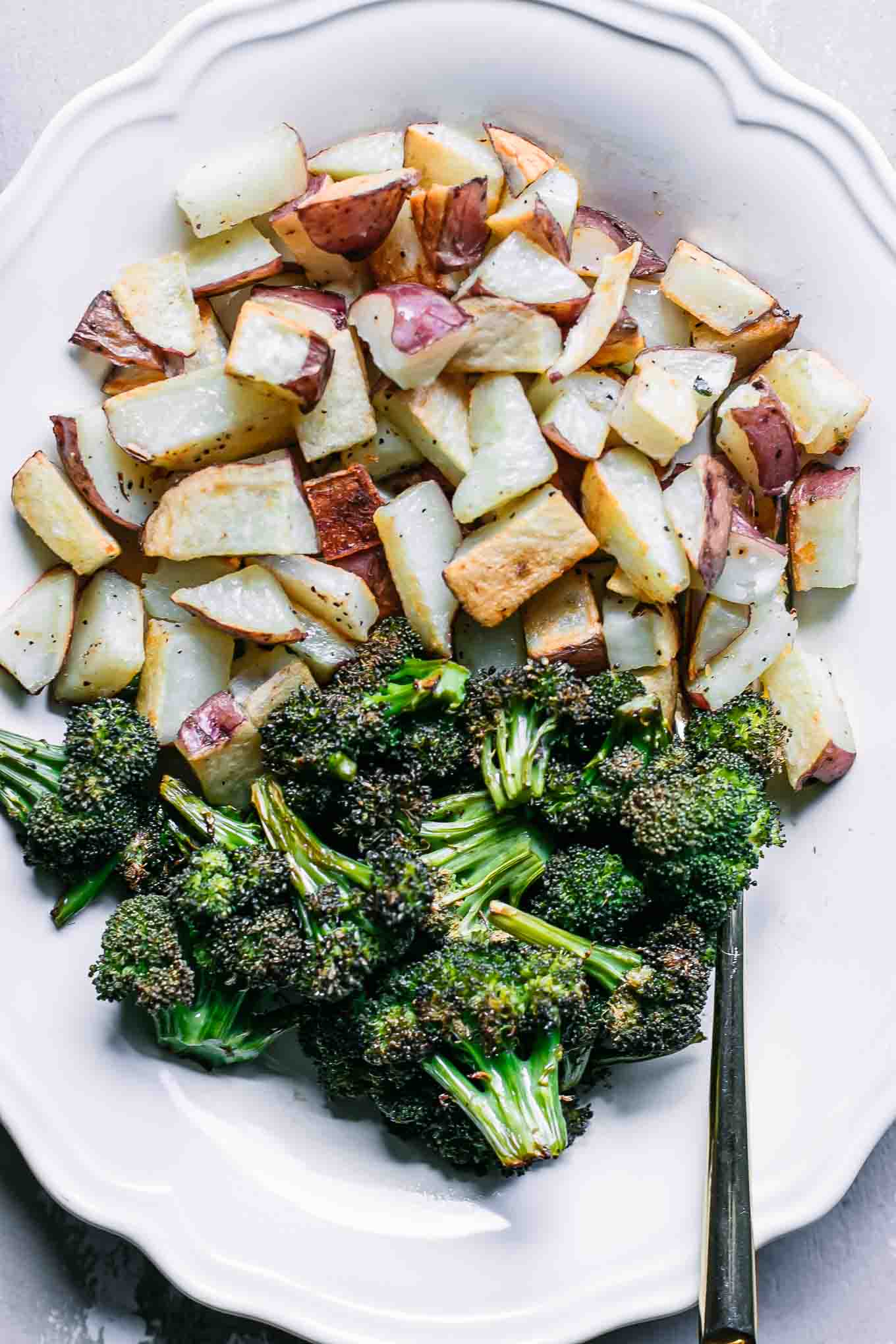 a close up photo of baked broccoli and potatoes with a gold fork