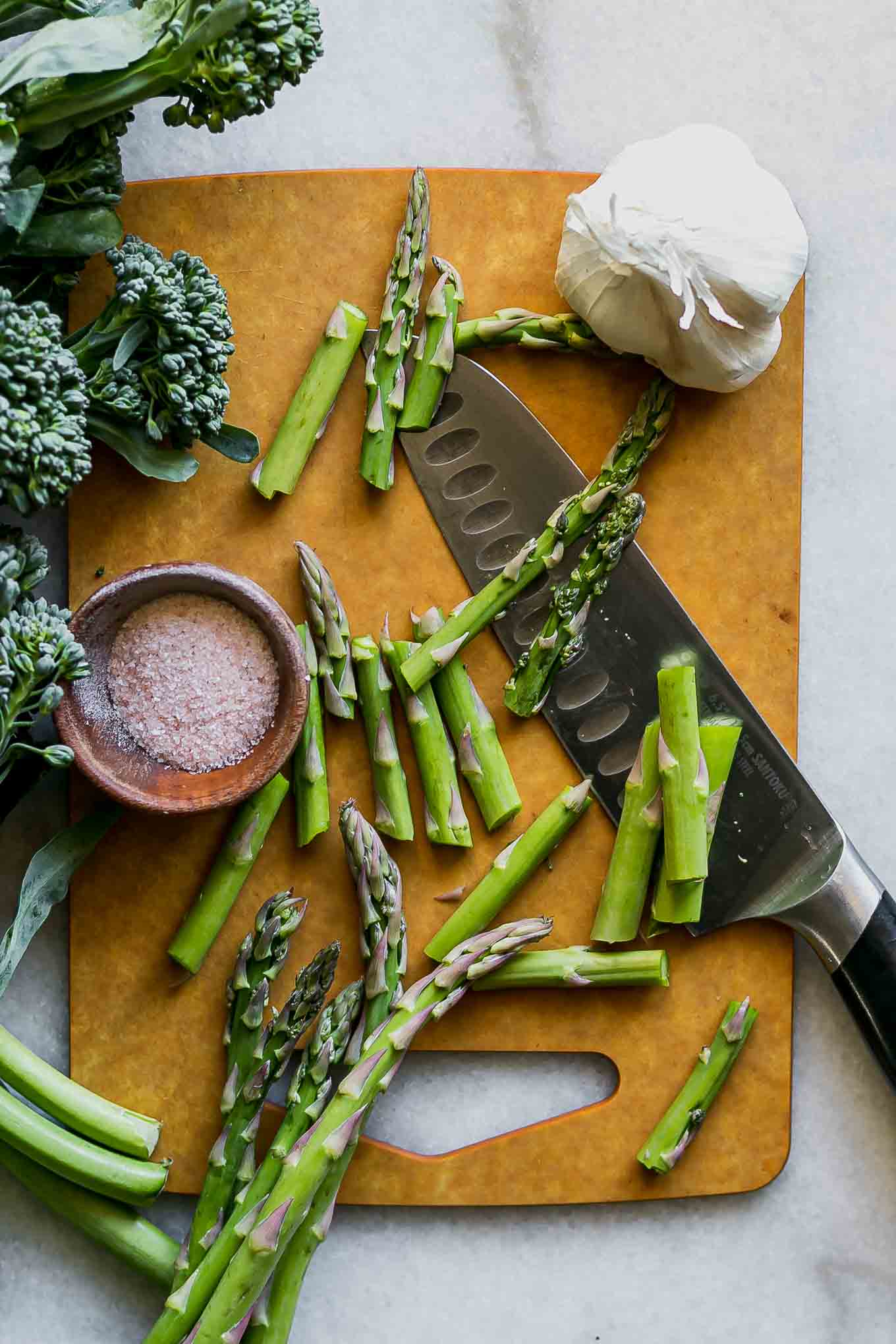 cut asparagus and broccolini on a wood cutting board