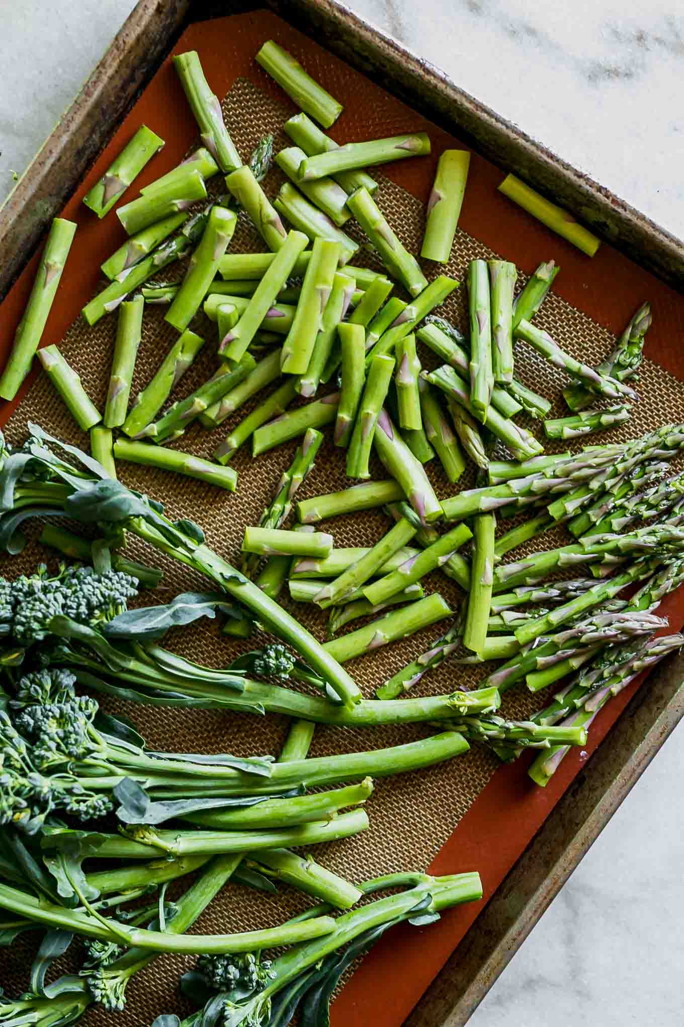 cut asparagus and broccolini on a baking sheet before roasting