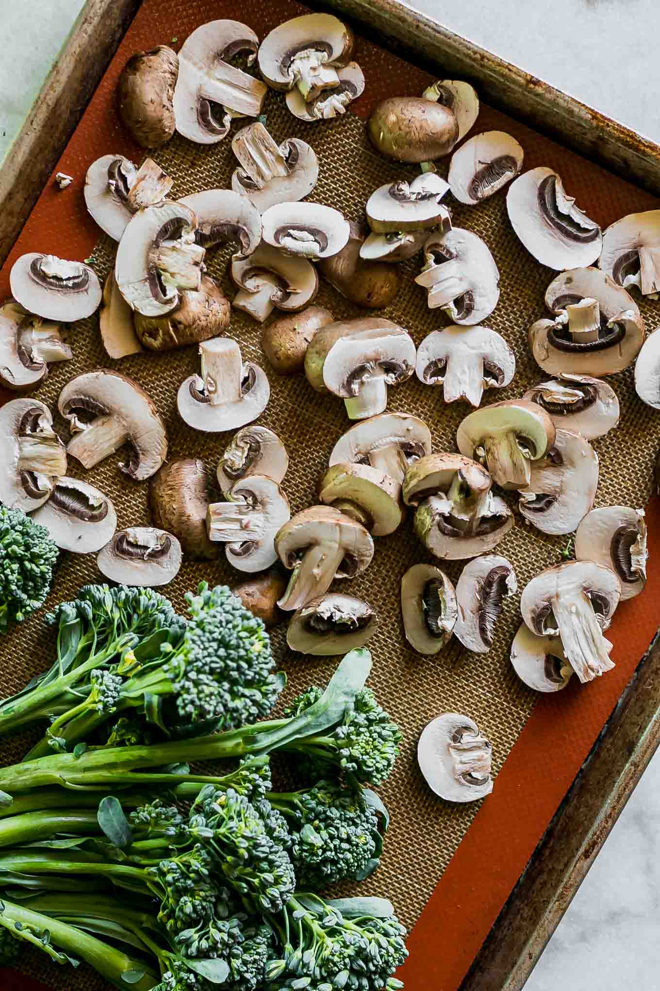 cut mushrooms and broccolini on a baking sheet before roasting