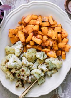 roasted cauliflower and butternut squash on a white plate with a gold fork
