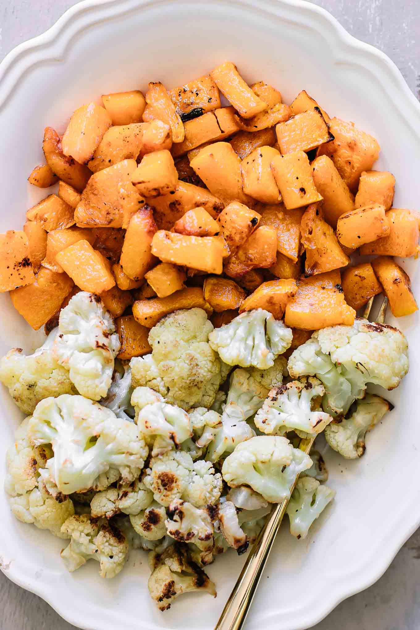a close up photo of butternut squash and cauliflower on a white plate