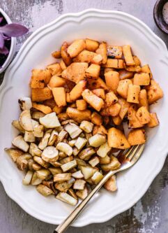 roasted parsnips and butternut squash on a white plate with a gold fork