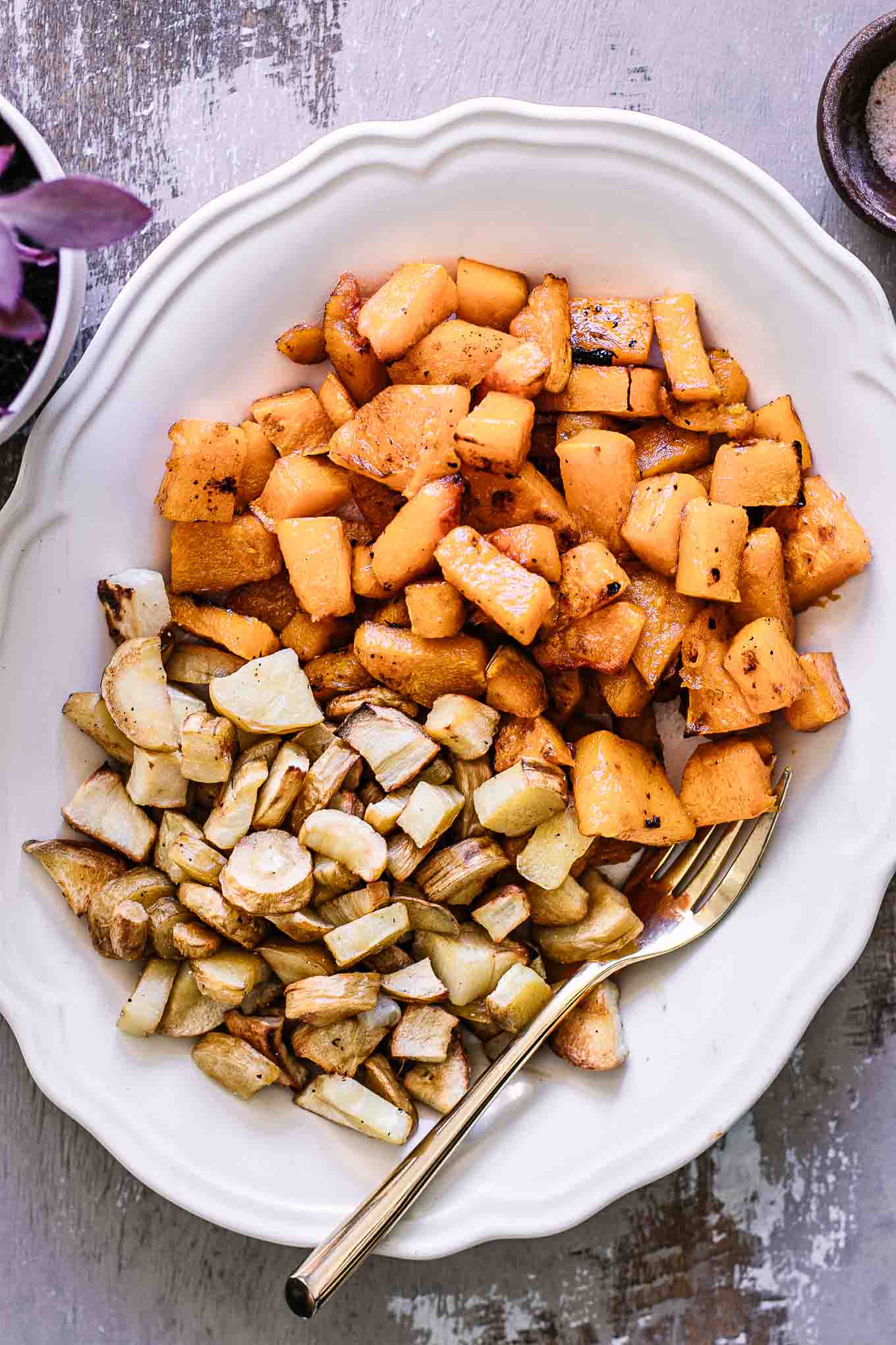 roasted parsnips and butternut squash on a white plate with a gold fork